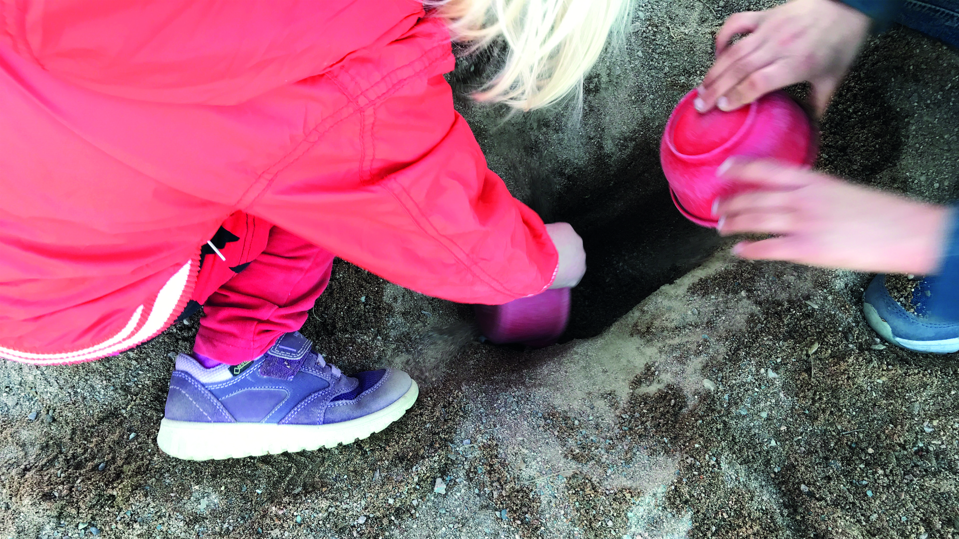 Två barn gräver i sandlådan.